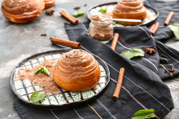Plate with tasty cinnamon bun on table