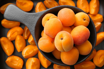 Pan with tasty apricots on table