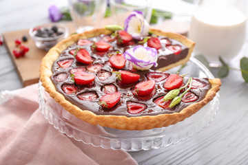 Stand with tasty chocolate strawberry cake on table