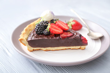 Plate with piece of tasty chocolate strawberry cake on white table