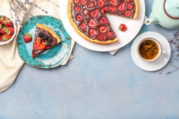 Tasty chocolate strawberry cake with tea on color background