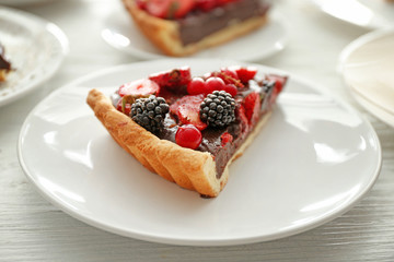 Plate with piece of tasty chocolate strawberry cake on white table