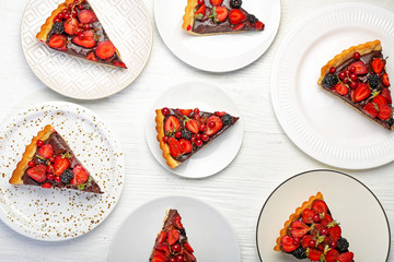 Plates with pieces of tasty chocolate strawberry cake on white table