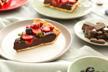 Plate with piece of tasty chocolate strawberry cake on table