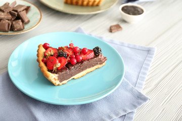 Plate with piece of tasty chocolate strawberry cake on table