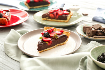 Plate with piece of tasty chocolate strawberry cake on table