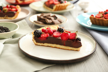 Plate with piece of tasty chocolate strawberry cake on table