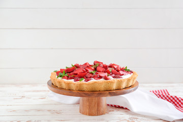 Tasty strawberry cake on white wooden table