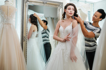 Beautifu bride choosing wedding dress in a wedding salon