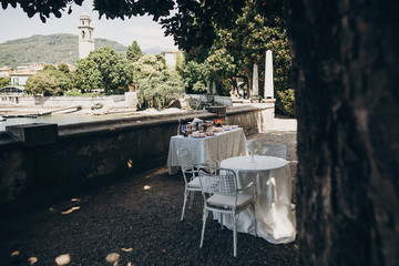 Delicious italian appetizers on table at wedding reception outdoors. Canapes and champagne, fruits on table at sea shore in Italy Stresa, wedding or  feast. Luxury catering outdoors