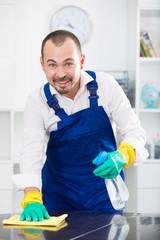 Young man in apron cleaning table