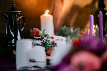 Delicate wedding white cake decorated with pomegranate and succulent surrounded by flowers and candles.