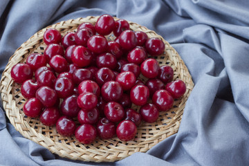 Ripe cherry in a wicker plate. Top view. Food background.