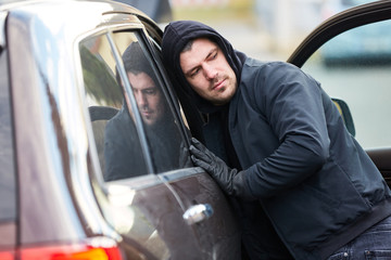 Mann als Dieb am offenen Auto