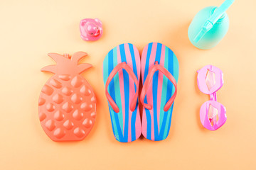 Vacation on the beach concept with colorful summer beach accessories - ananas shape frozen liquid block, flip flops, funny glasses, water spray