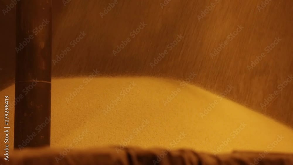 Poster granular particles ejected from machine in industrial plant. static footage of loading within a fert