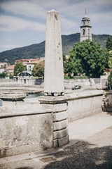 Beautiful old architecture on shore of Lago Maggiore in Stresa city, Italy. Green pier on Lago Maggiore on background of old buildings and mountains. Summer vacation in Europe