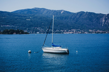 Beautiful white boats sailing on Lago Maggiore, Stresa city, Italy. Relaxing on yacht on Lago Maggiore on background of sunny mountains. Summer vacation in Europe. Space for text