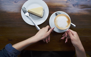 woman holding a cup of coffee in her hands with cake