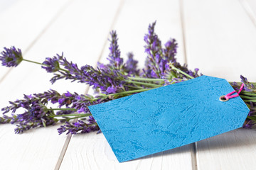 Bunch of freshly picked lavender,  with a blank gift label.  White wood background