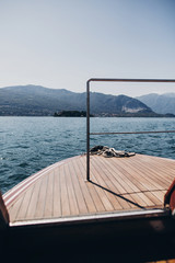 Beautiful yacht wooden deck, boat nose, sailing to Borromean Islands on Lago Maggiore, Stresa city, Italy. Relaxing on lake Maggiore. Summer vacation in Europe