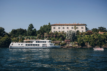 Beautiful view on Borromean Islands  and boats on lake from Stresa, vacation in Italy. Isole Borromee on Lago Maggiore in sunny day on background of mountains. Summer travel in Europe