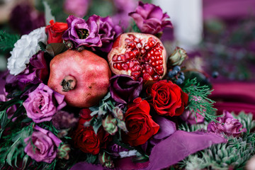 Wedding asymmetrical stylish bouquet with red roses and pomegranate.