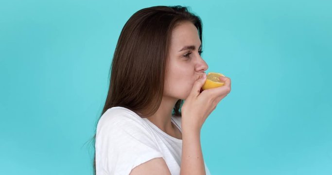 Brunette girl bites lemon. Portrait in profile. Yellow sour lemon.