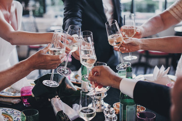 Group of people holding champagne glasses and toasting at wedding reception outdoors in the...