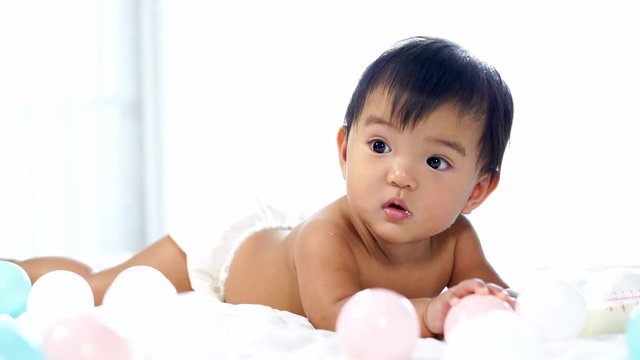 cheerful baby playing color ball on a bed