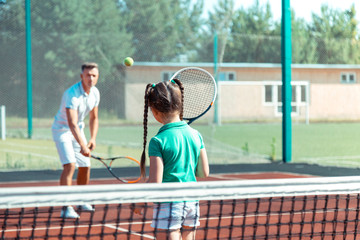Daughter feeling involved in playing tennis with father