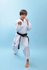 Young karate woman in a white kimono with black belt demonstrates fighting stances and strikes....