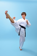 Young karate woman in a white kimono with black belt demonstrates fighting stances and strikes. Girl at studio shows martial arts © Khorzhevska