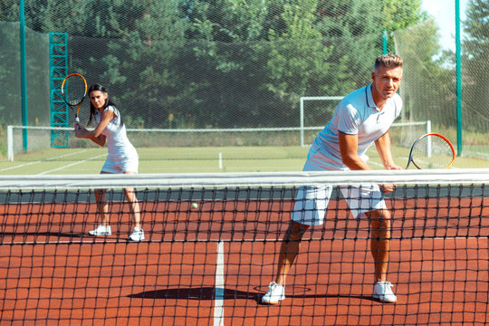 Couple feeling joyful while training on court playing tennis