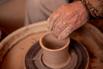 potter's hands work with clay, making it a product