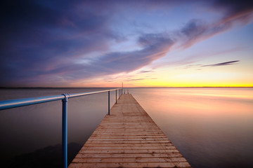 Fototapeta na wymiar Rydebäck small pier with blue hand rail at sunset