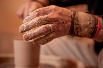 potter's hands work with clay, making it a product