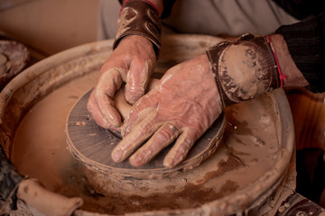 potter's hands work with clay, making it a product