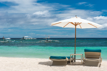 Tropical beach background from Alona Beach at Panglao Bohol island with Beach chairs on the white sand beach with cloudy blue sky and palm trees. Travel Vacation