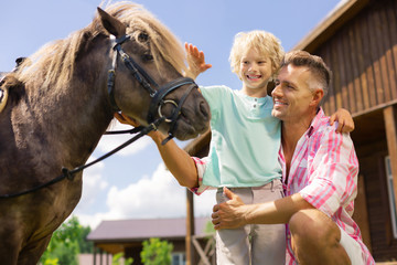 Son smiling while touching horse for the first time