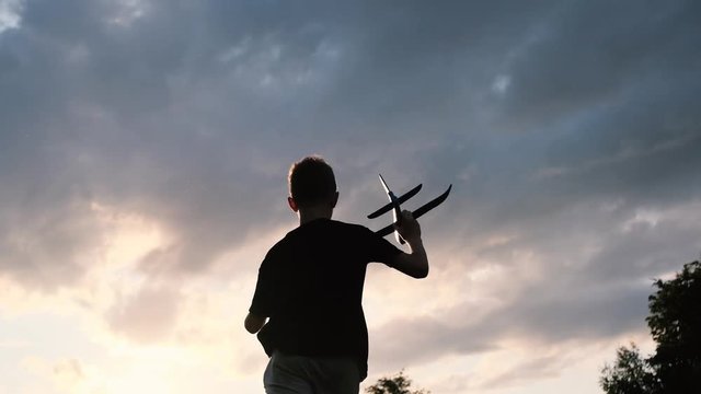 The boy is playing with a toy plane. Sunset. Slow motion.