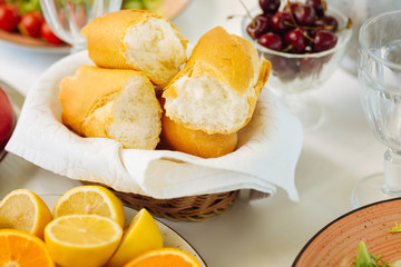 Pieces of baguette lying in bowl near lemons and cherries