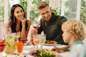 Beaming parents smiling while listening to their cute smart son