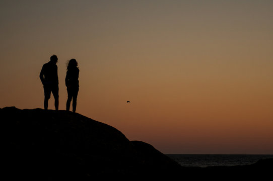 Portrait of couple silhouettes looking ocean on sunst background