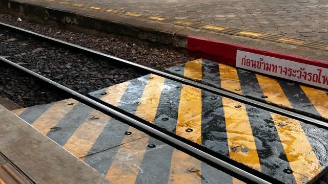 Crosswalk between the rail roads with the yellow and black strip at Lampang Station, Thailand.