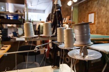 White threads in a vintage overlock. A closeup view of thread spools attached to an old-fashioned overlocking machine inside a dressmaker's studio, ready to create seams.