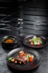 grilled juicy steak with grilled mushrooms, tomatoes and cranberries on a dark round plate