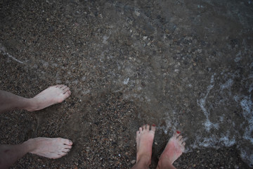 Pies de chico y de chica en la orilla del mar