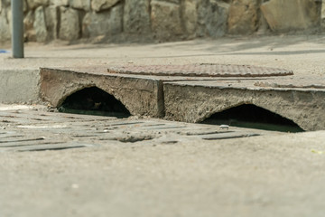 Sewer manhole for drains, grate close-up on a sunny day