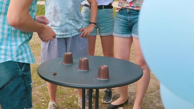 Street magician with cups. People guess the cup you want